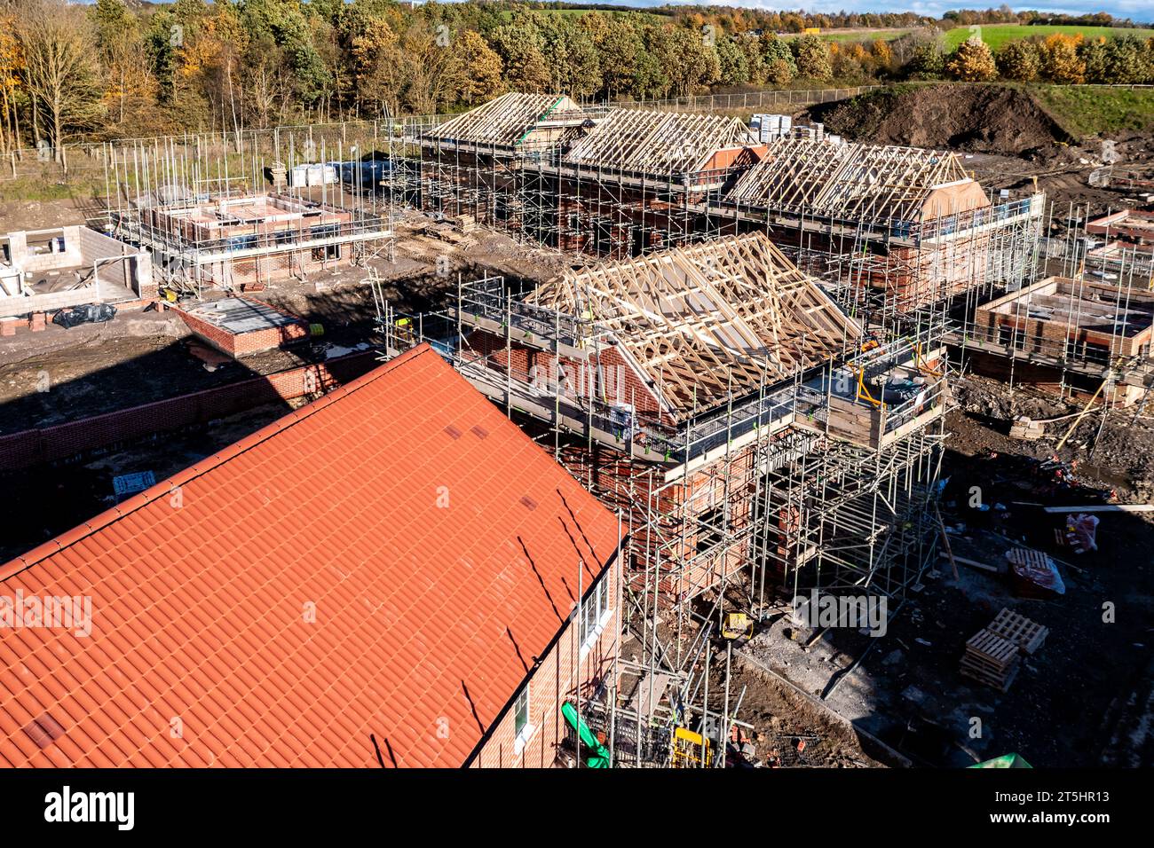 Vue aérienne d'un chantier de construction avec de nouvelles maisons écoénergétiques construites avec les chevrons de toit exposés et entourés par un échafaudage avec co Banque D'Images