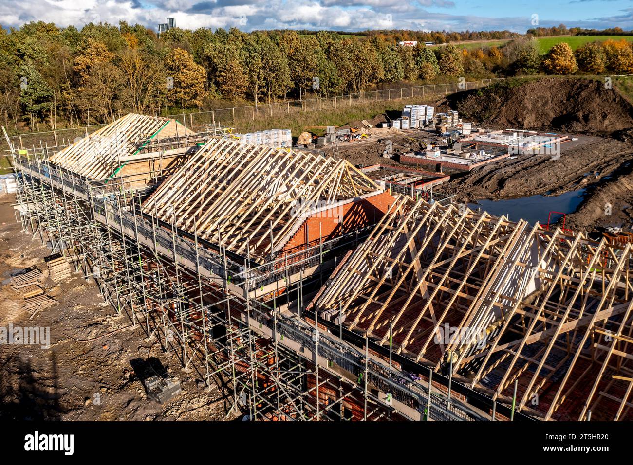 Vue aérienne d'un chantier de construction avec de nouvelles maisons écoénergétiques construites avec les chevrons de toit exposés et entourés par un échafaudage avec co Banque D'Images