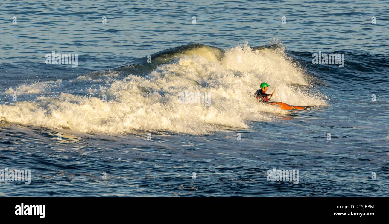 Kayak de mer chevauchant une grande vague Banque D'Images