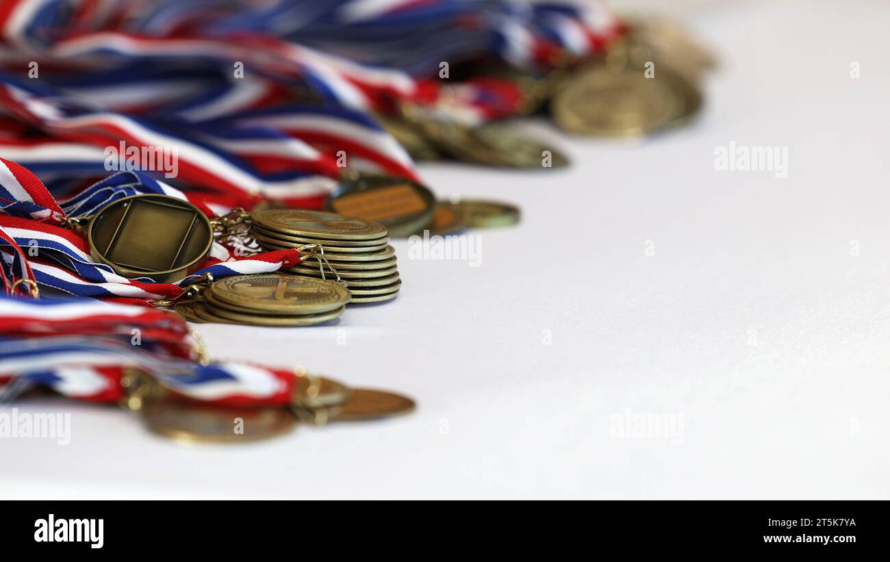 Une pile de médailles et de rubans étalés prêts à être décernés à des équipes sportives ou à des athlètes. Remise de prix à l'école ou au club ou cérémonie de remise de médailles Banque D'Images