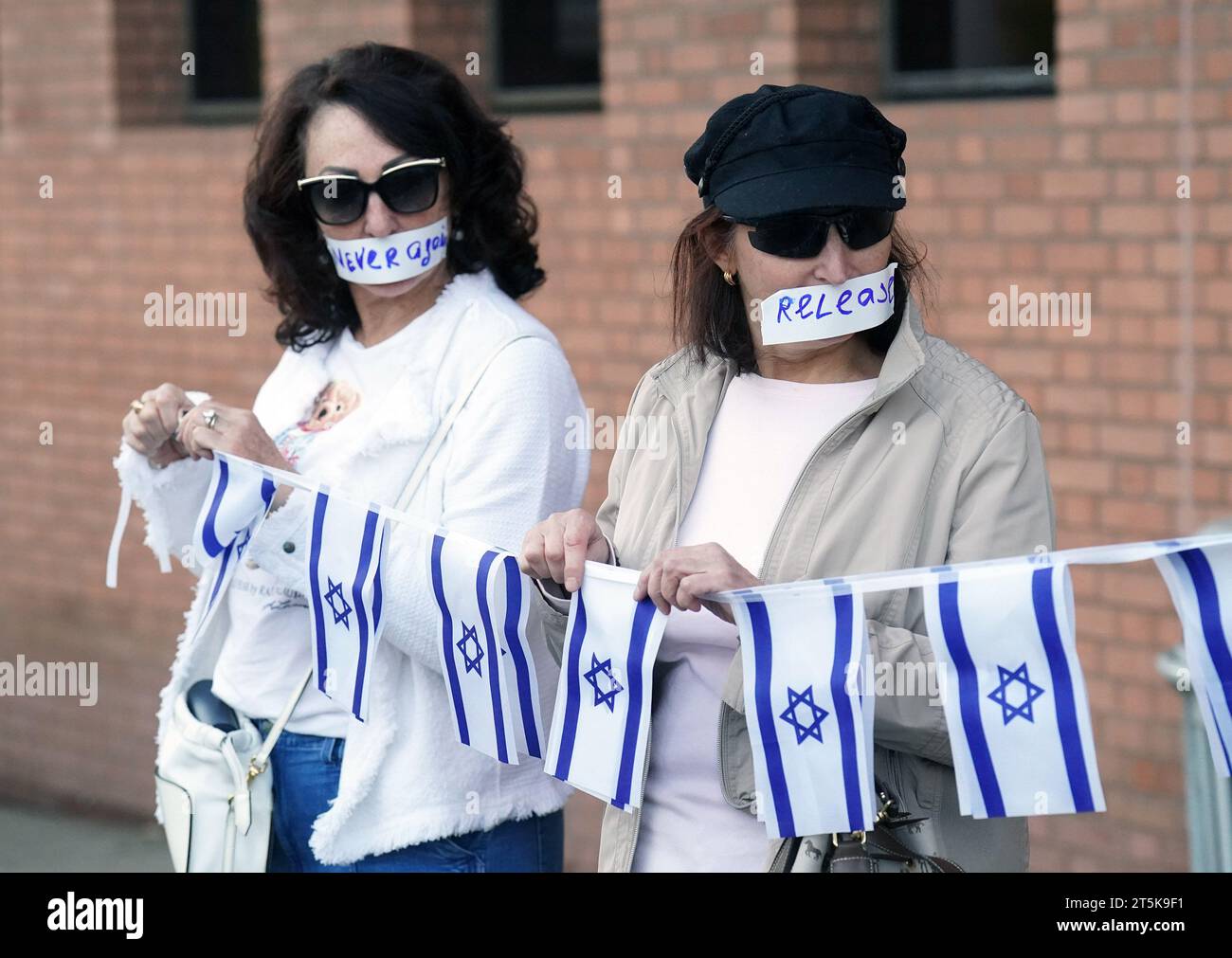 Clayton, États-Unis d'Amérique. 05 novembre 2023. Des femmes se tiennent en silence tenant de petits drapeaux d'Israël pendant 45 minutes avec d'autres lors d'un rassemblement montrant leur soutien à Israël, à Clayton, Missouri, le dimanche 5 novembre 2023. Après des paroles d'encouragement et de prières, environ 200 partisans d'Israël se tenaient près d'une rue animée avec du ruban adhésif sur la bouche avec un mot qu'ils ont choisi, pour exprimer leur opinion sur les événements actuels au Moyen-Orient. Photo de Bill Greenblatt/UPI crédit : UPI/Alamy Live News Banque D'Images