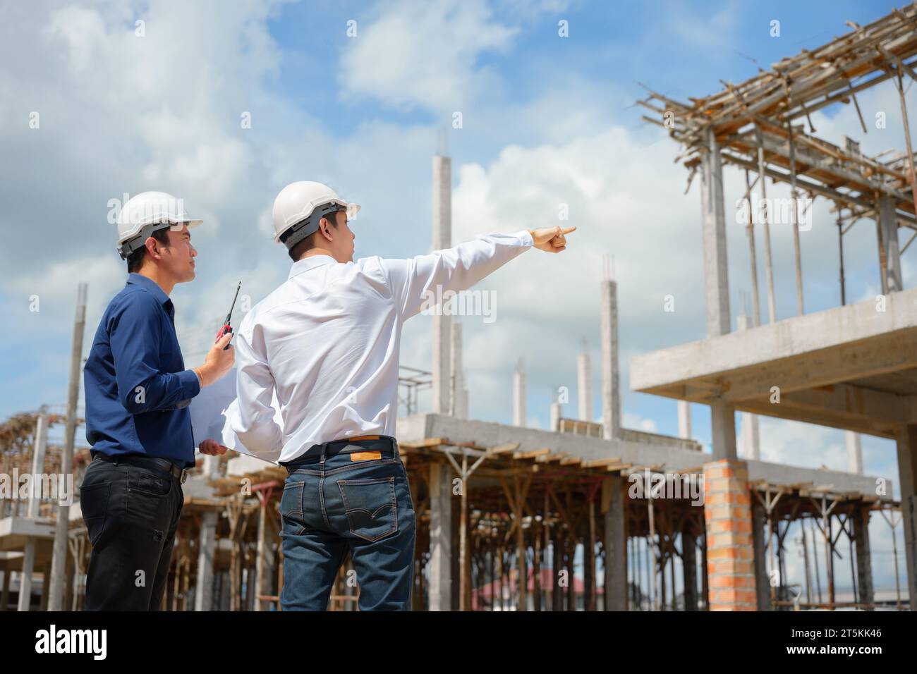 Deux ingénieurs en vêtements réfléchissants examinent le plan et discutent  du projet ensemble tout en travaillant sur le chantier de construction  Photo Stock - Alamy