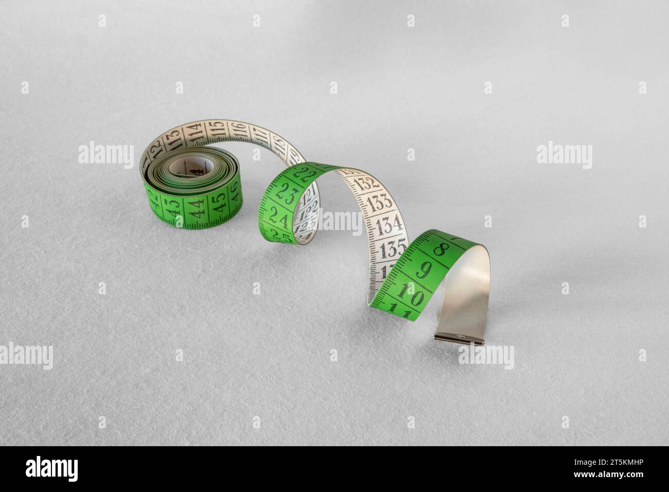 Gros plan d'un ruban à mesurer en spirale vert sur fond blanc Banque D'Images