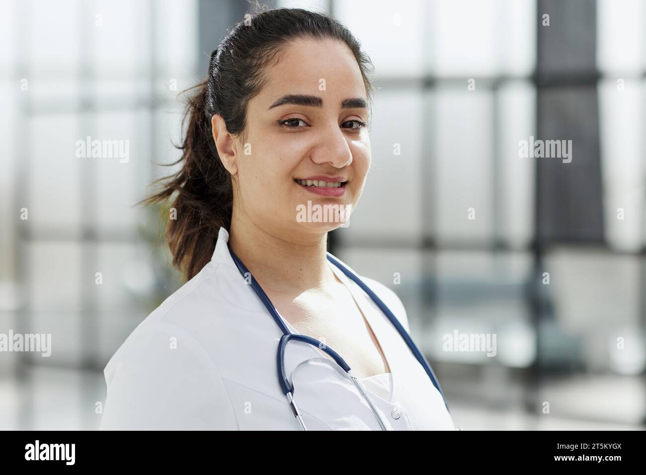 Femme dentiste debout avec les bras croisés. Dentiste confiant debout dans un couloir d'hôpital dans un manteau blanc. Banque D'Images