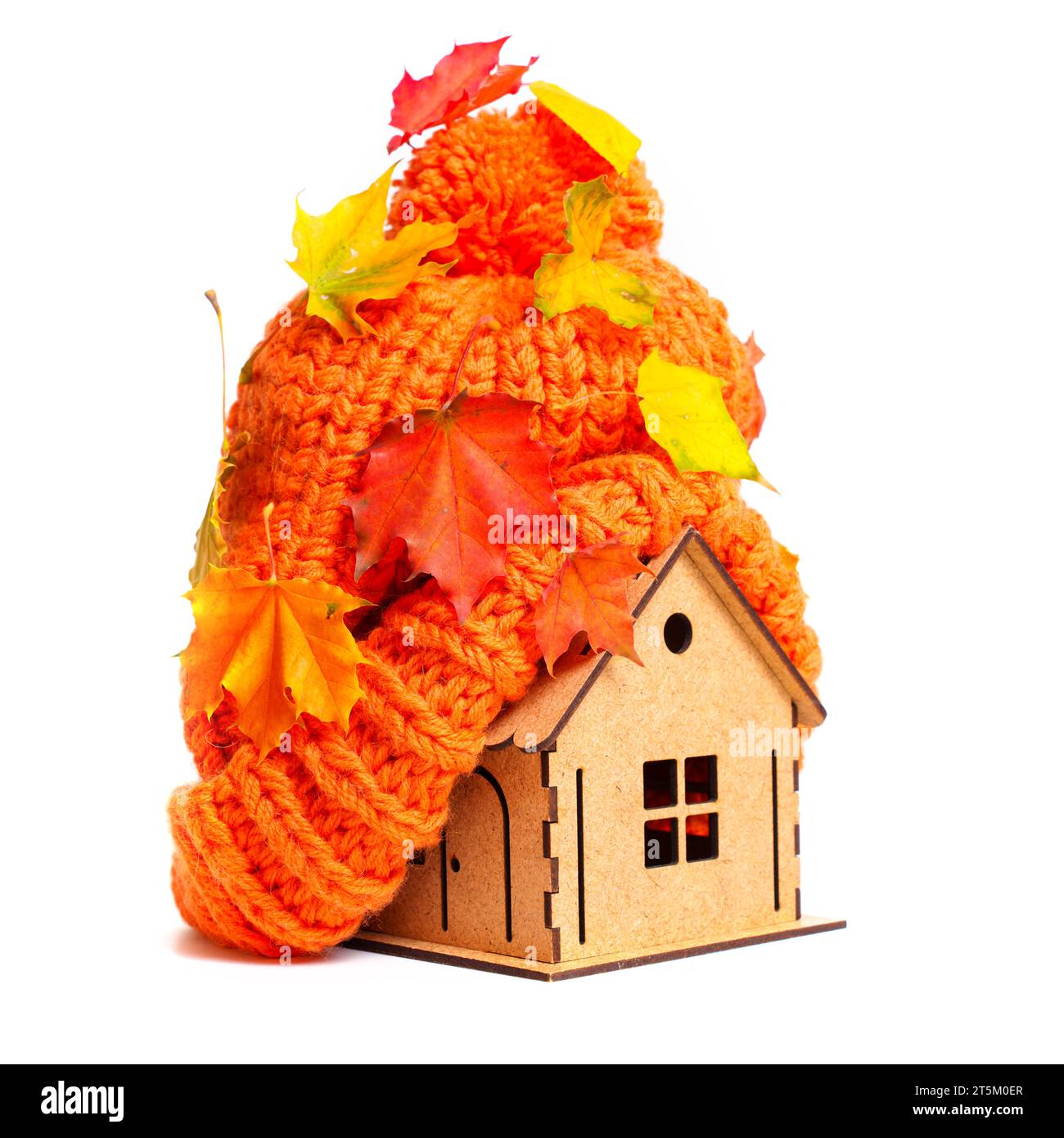 Gros plan d'un minuscule modèle de maison en bois avec un chapeau orange épais sur le dessus recouvert de feuilles pigmentées isolées sur fond blanc. Chauffage et insulatio Banque D'Images