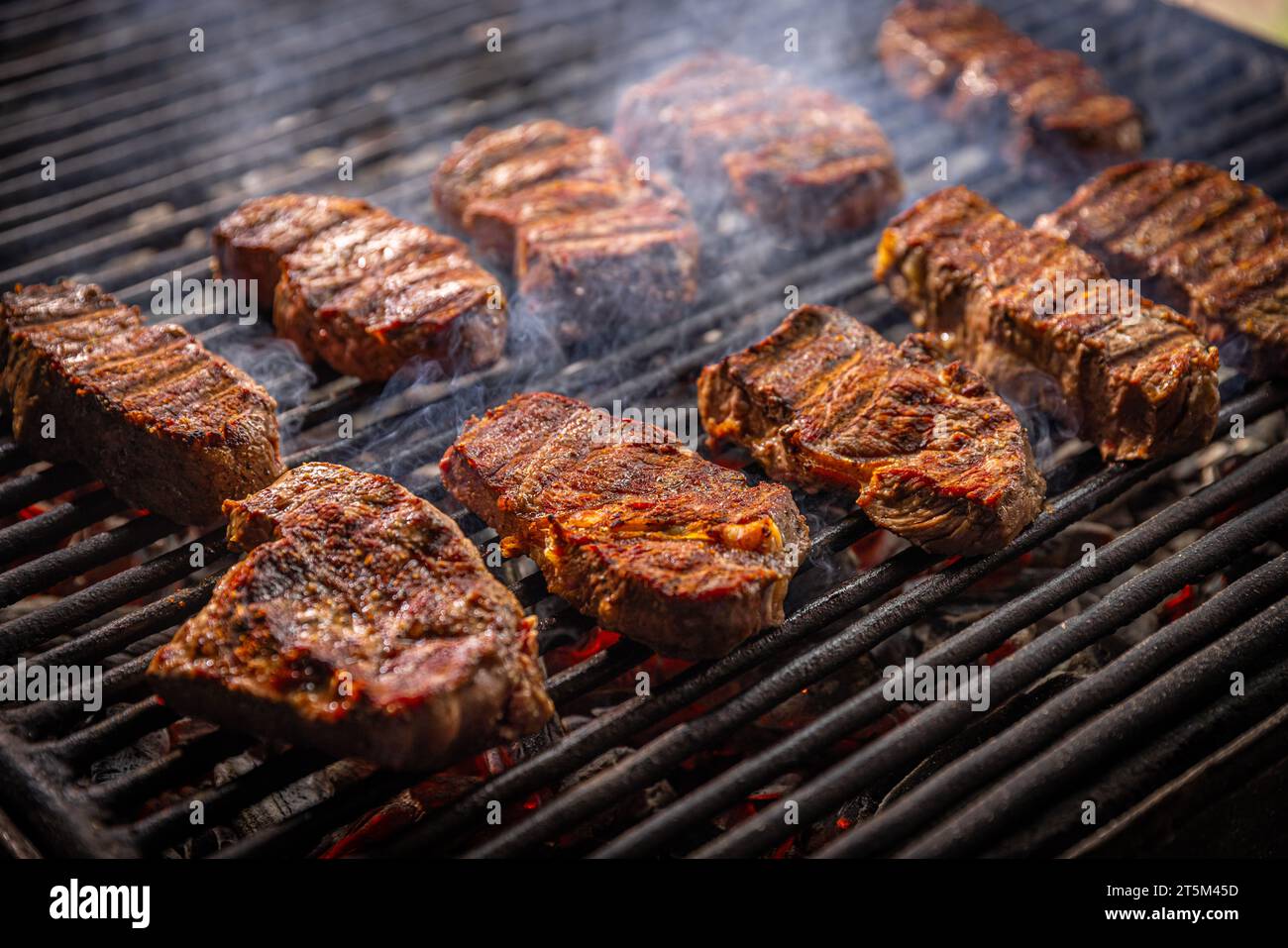 Plusieurs morceaux de steak grésillent sur un gril Banque D'Images