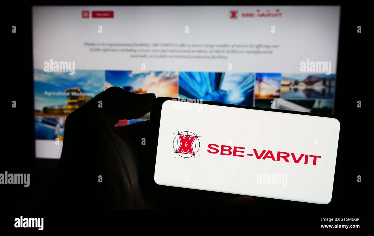 Personne détenant un téléphone portable avec le logo de la société italienne de fixation mécanique SBE-VARVIT S.p.A. devant la page web. Concentrez-vous sur l'affichage du téléphone. Banque D'Images