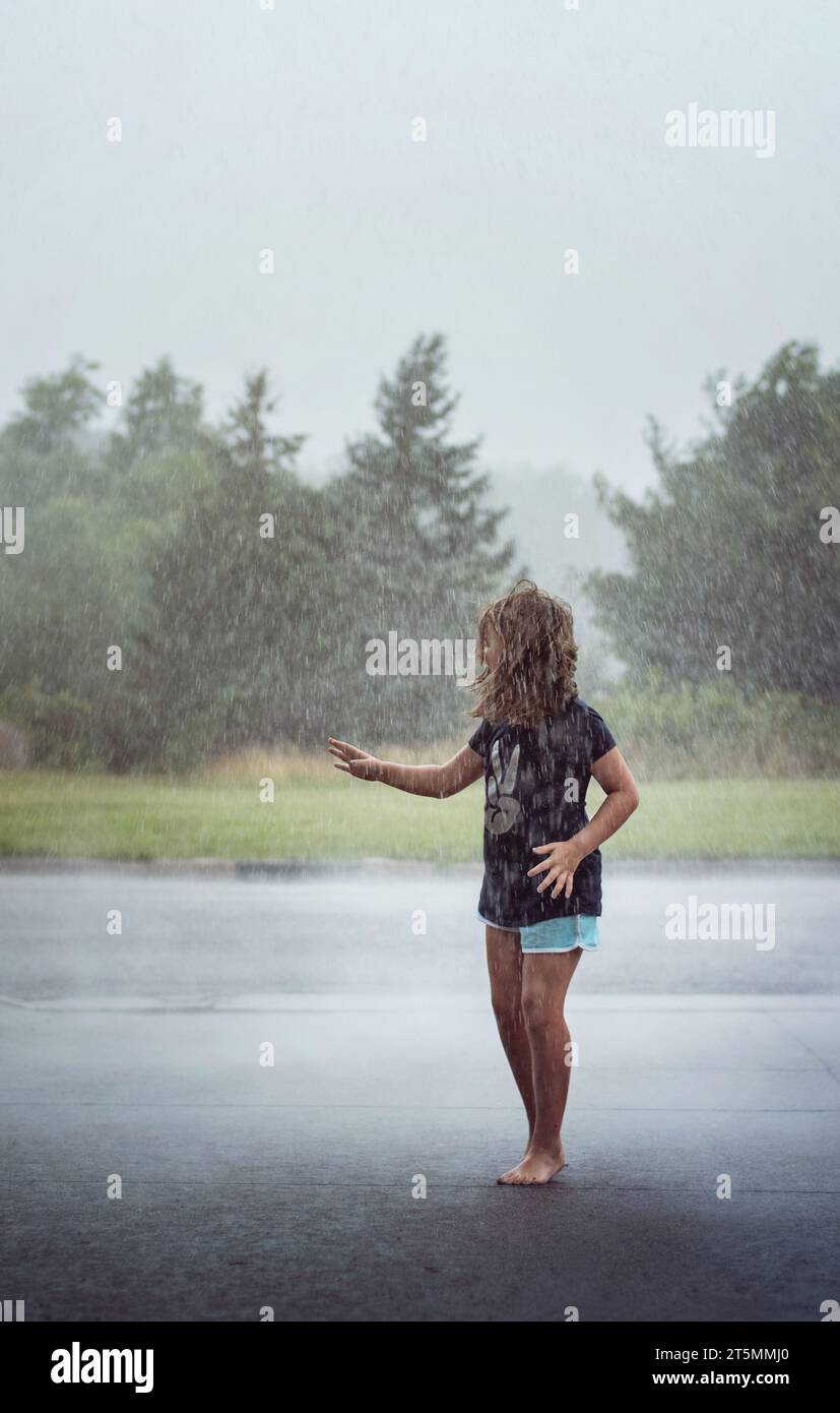 Jeune fille jouant sous la pluie en été Banque D'Images