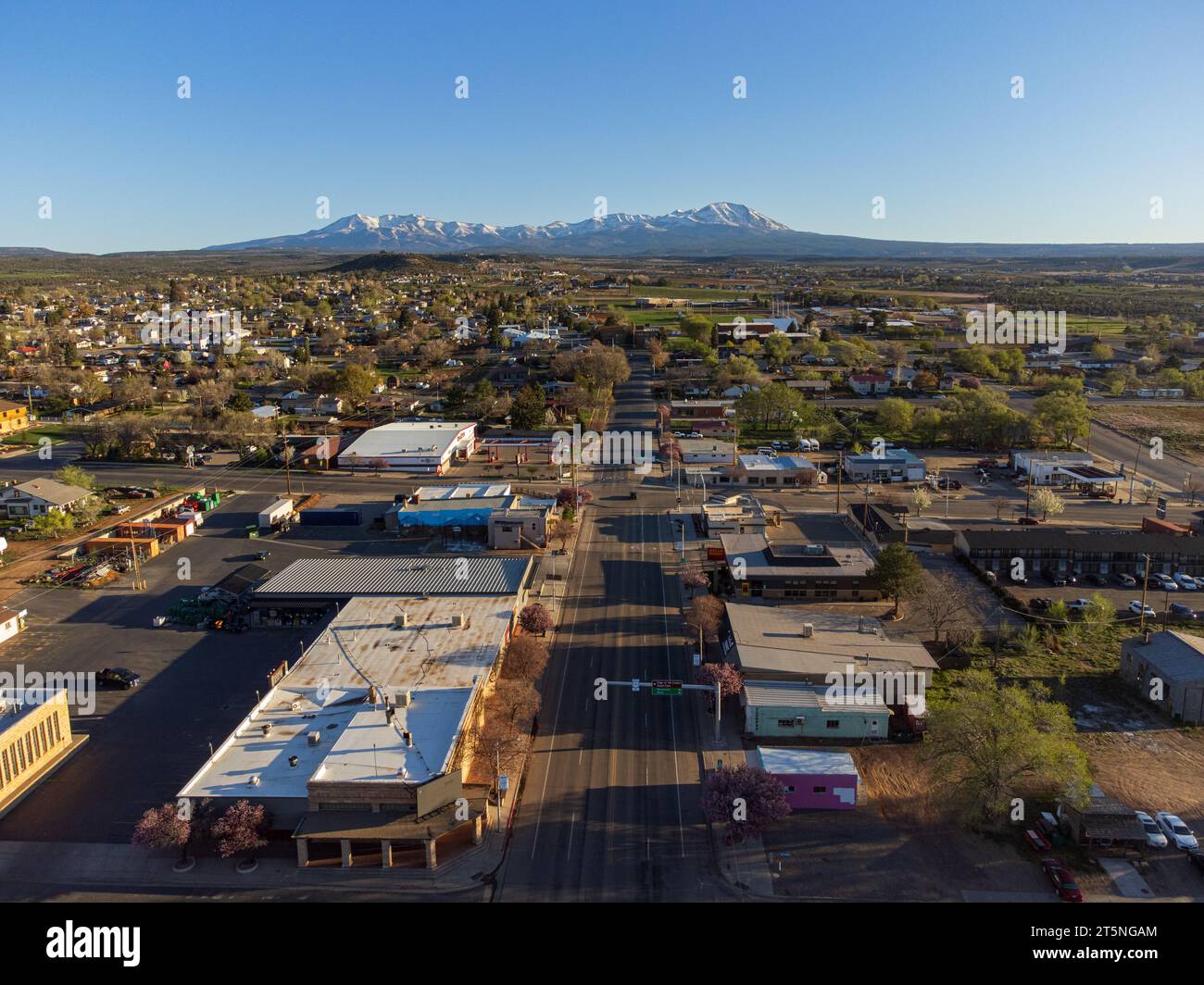 Vue panoramique de la petite ville rurale de Blanding, Utah au moment de la floraison printanière, ciel bleu et montagnes enneigées. Banque D'Images