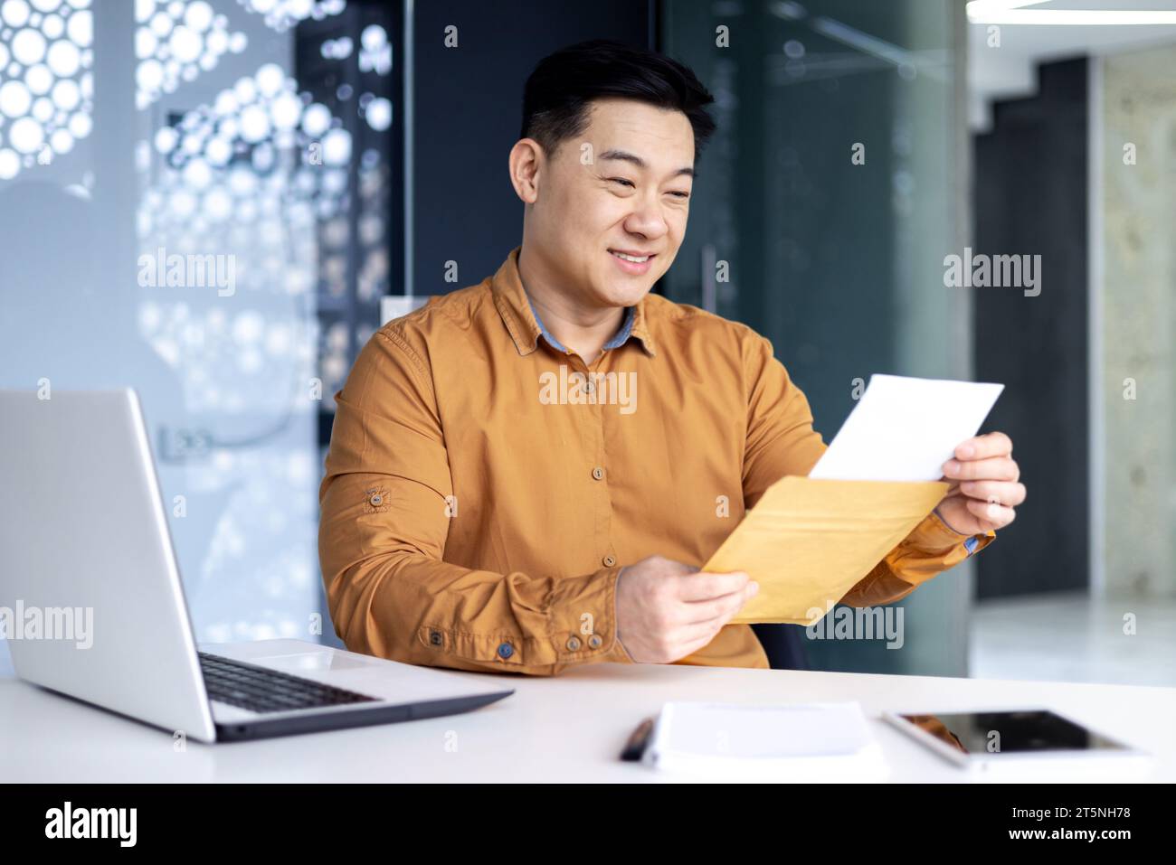 Homme d'affaires réussi a reçu un message de notification de courrier, homme asiatique lisant, souriant tenant dans le renard. Homme travaillant à l'intérieur du bureau avec ordinateur portable, d'excellents résultats de réalisation. Banque D'Images