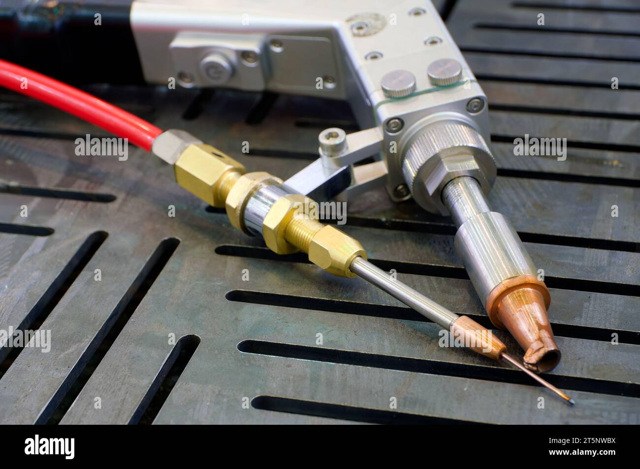 Outil de soudage par faisceau laser, torche collimateur portative, sur une table de travail en acier, gros plan. Banque D'Images