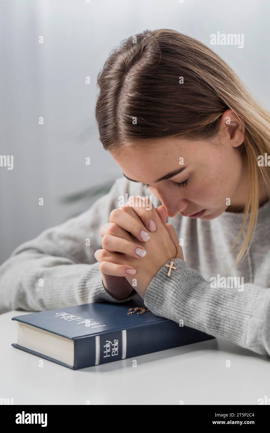 Femme priant avec collier de croix biblique Banque D'Images