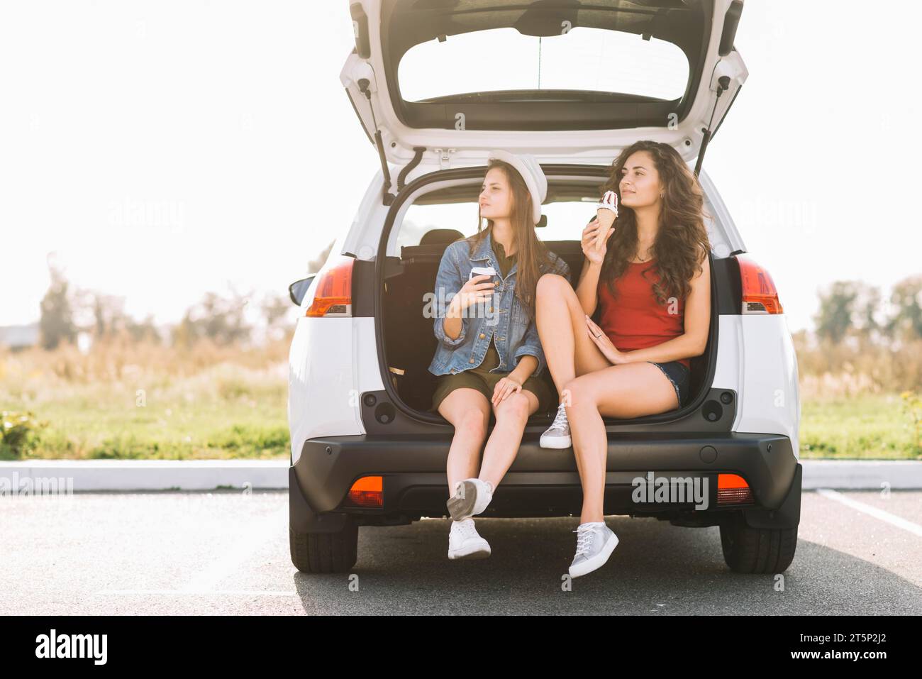 Jeunes femmes assises dans le coffre de voiture Banque D'Images