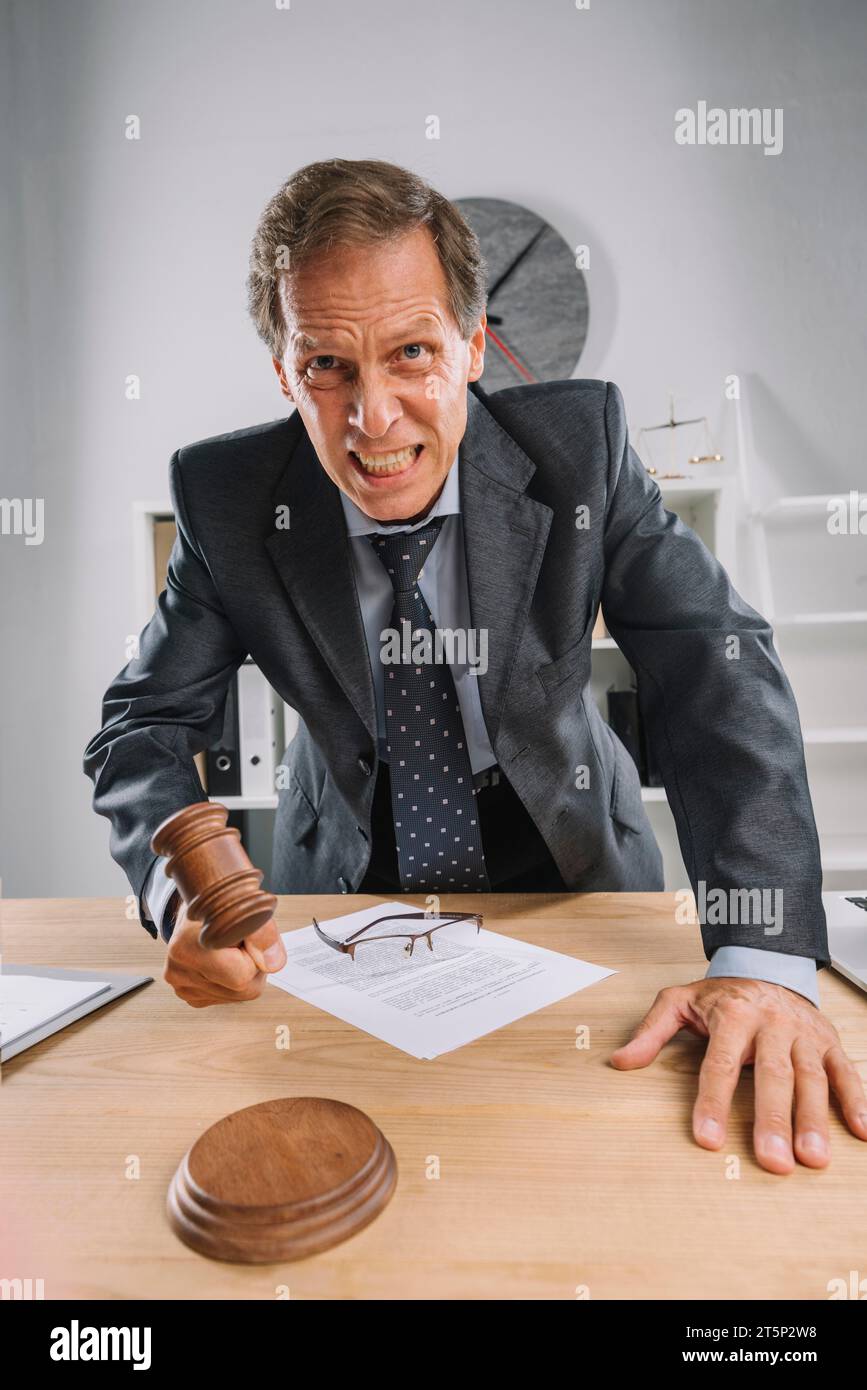 Juge mature en colère frappant sa salle d'audience de table de marteau Banque D'Images