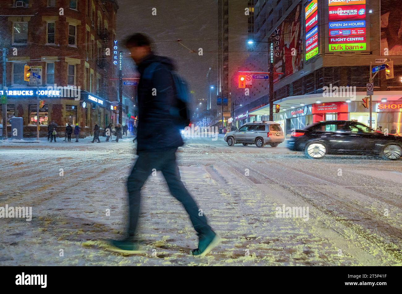 Toronto, Canada - 14 décembre 2013 : flou de mouvement d'une personne traversant une rue pendant une tempête de neige dans le quartier du centre-ville. Banque D'Images