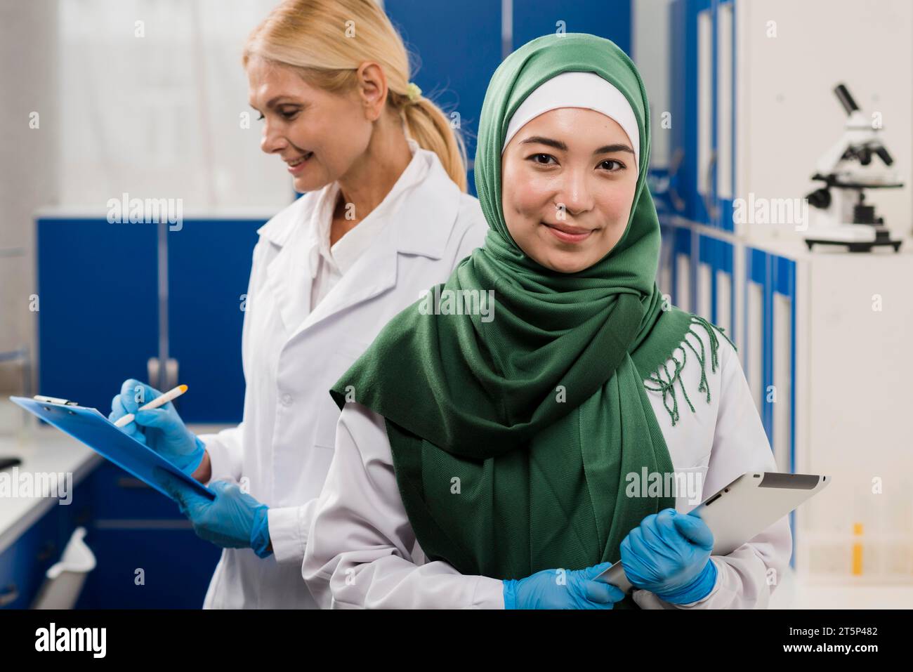 Vue de face femme scientifique avec hijab posant labo avec collègue Banque D'Images