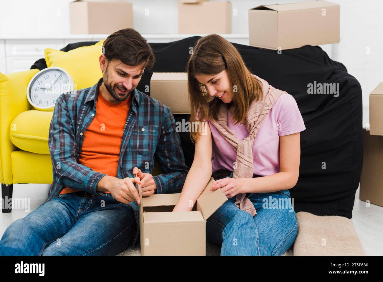 Jeune couple souriant assis près du canapé boîte à déballer nouvelle maison Banque D'Images