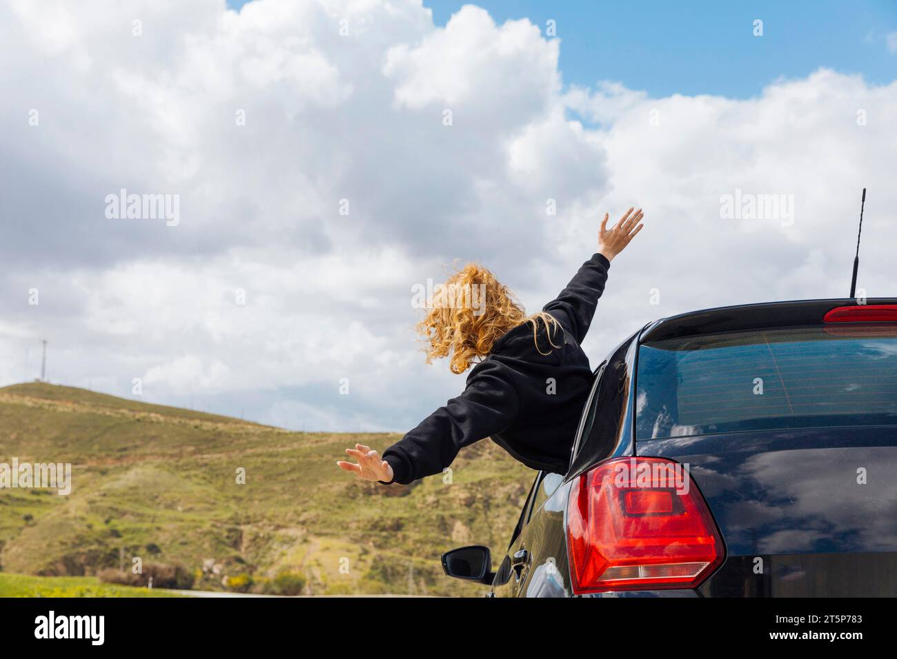 Jeune femme frisée penchée par la fenêtre de la voiture Banque D'Images