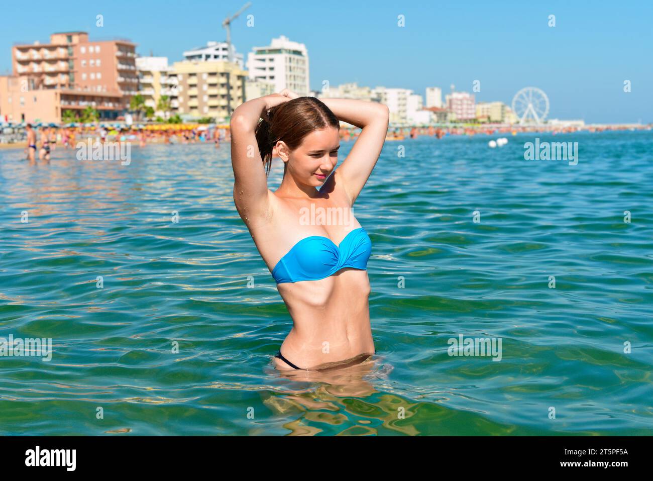 Fille en maillot de bain bleu prend un bronzage sur une plage tropicale. Banque D'Images