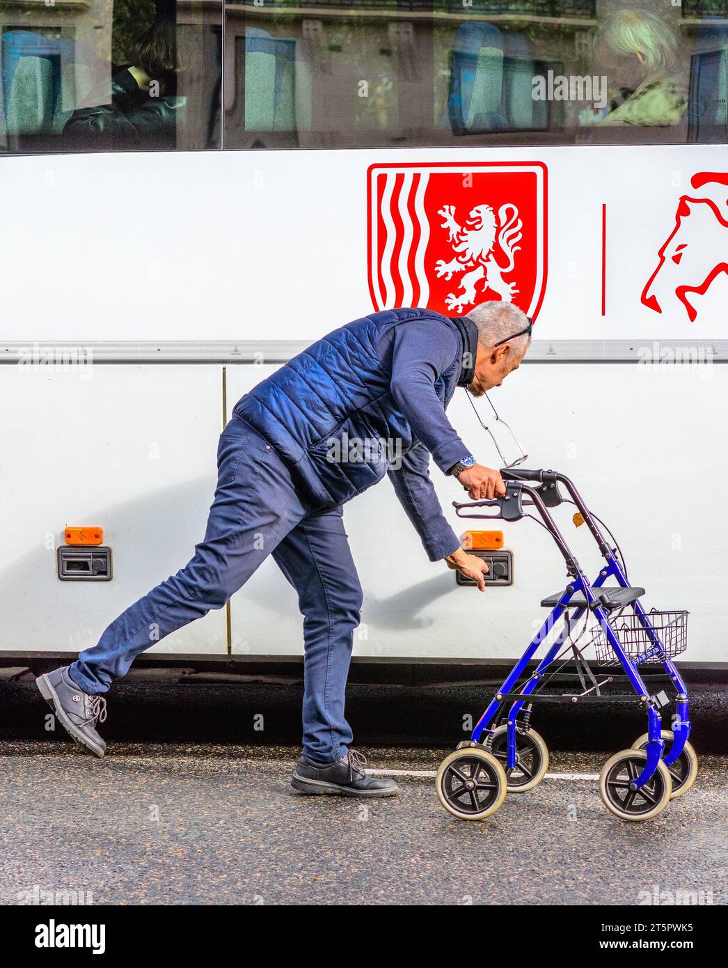 Homme (conducteur d'autobus) avec châssis roulant passager ouvrant le compartiment de rangement de l'autocar - Tours, Indre-et-Loire (37), France. Banque D'Images