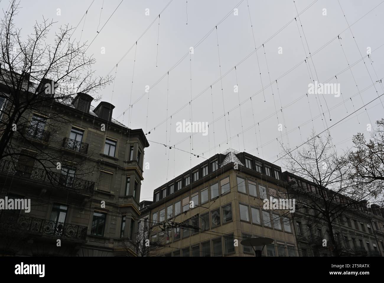 Éclairage extérieur de Noël dans le centre-ville de Zurich, Suisse. Les chaînes avec des lumières sont suspendues au-dessus des rues parmi les bâtiments. Banque D'Images