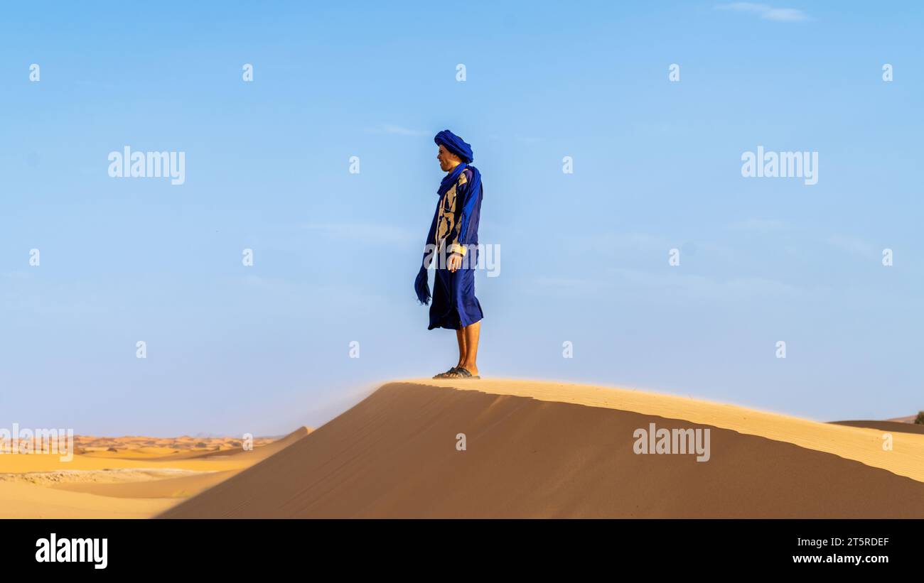 Désert du Sahara, Maroc - 13 septembre 2022 : Berbère debout sur une dune de sable dans ses vêtements traditionnels dans le désert du Sahara, Maroc Banque D'Images
