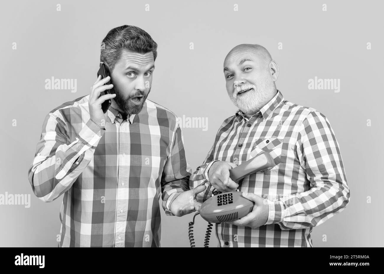 des hommes surpris par un appel téléphonique contrasté en studio. hommes avec appel téléphonique contrasté Banque D'Images