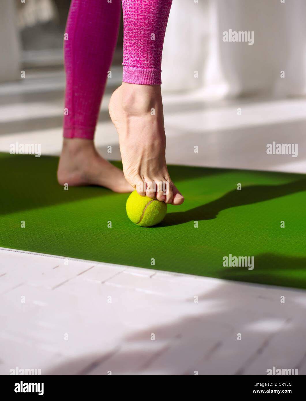 Massage aux balles de tennis pour les pieds. Femme pratiquant l'auto-massage des pieds avec une balle de tennis. Physiothérapie, réflexologie. Soulagement de la tension plantaire Banque D'Images