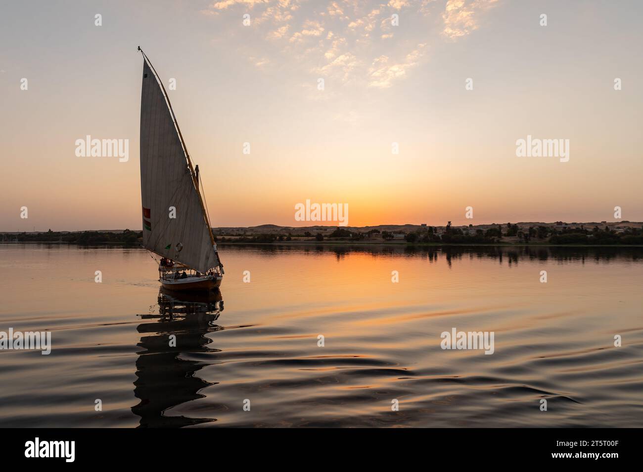Bateau à voile égyptien de style traditionnel felouque descend le fleuve au coucher du soleil sur le Nil Banque D'Images