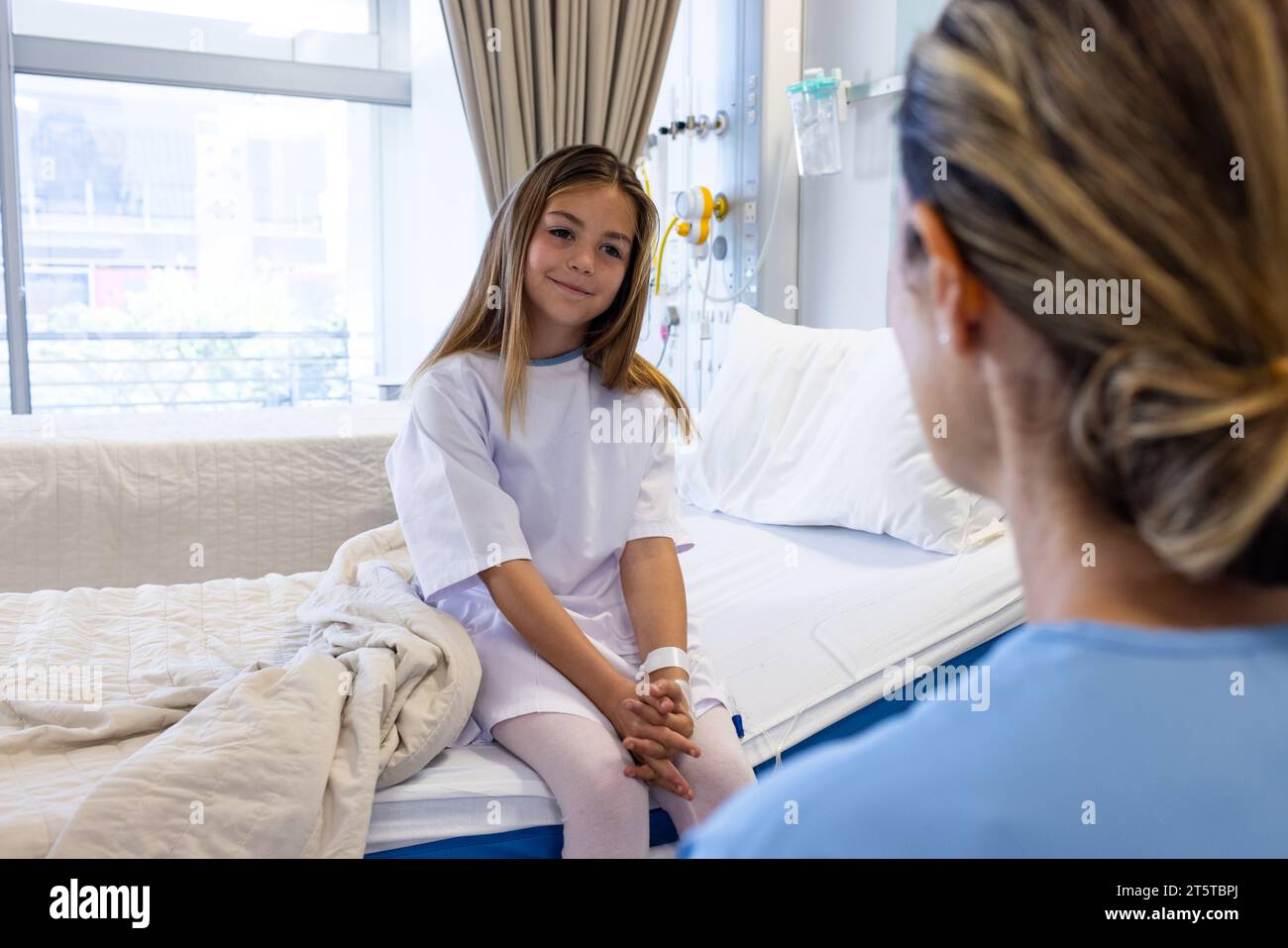 Souriante patiente caucasienne assise sur des lits d'hôpital parlant avec un médecin féminin Banque D'Images