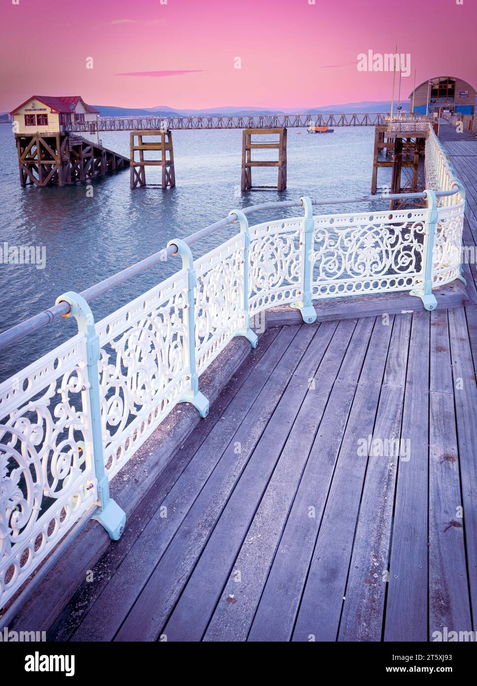 Le Mumbles Pier à Swansea, pays de Galles à l'aube / coucher du soleil avec des tons pastel, look épuré avec la beauté du paysage marin et la pertinence historique. Embarcadère emblématique pour les touristes Banque D'Images