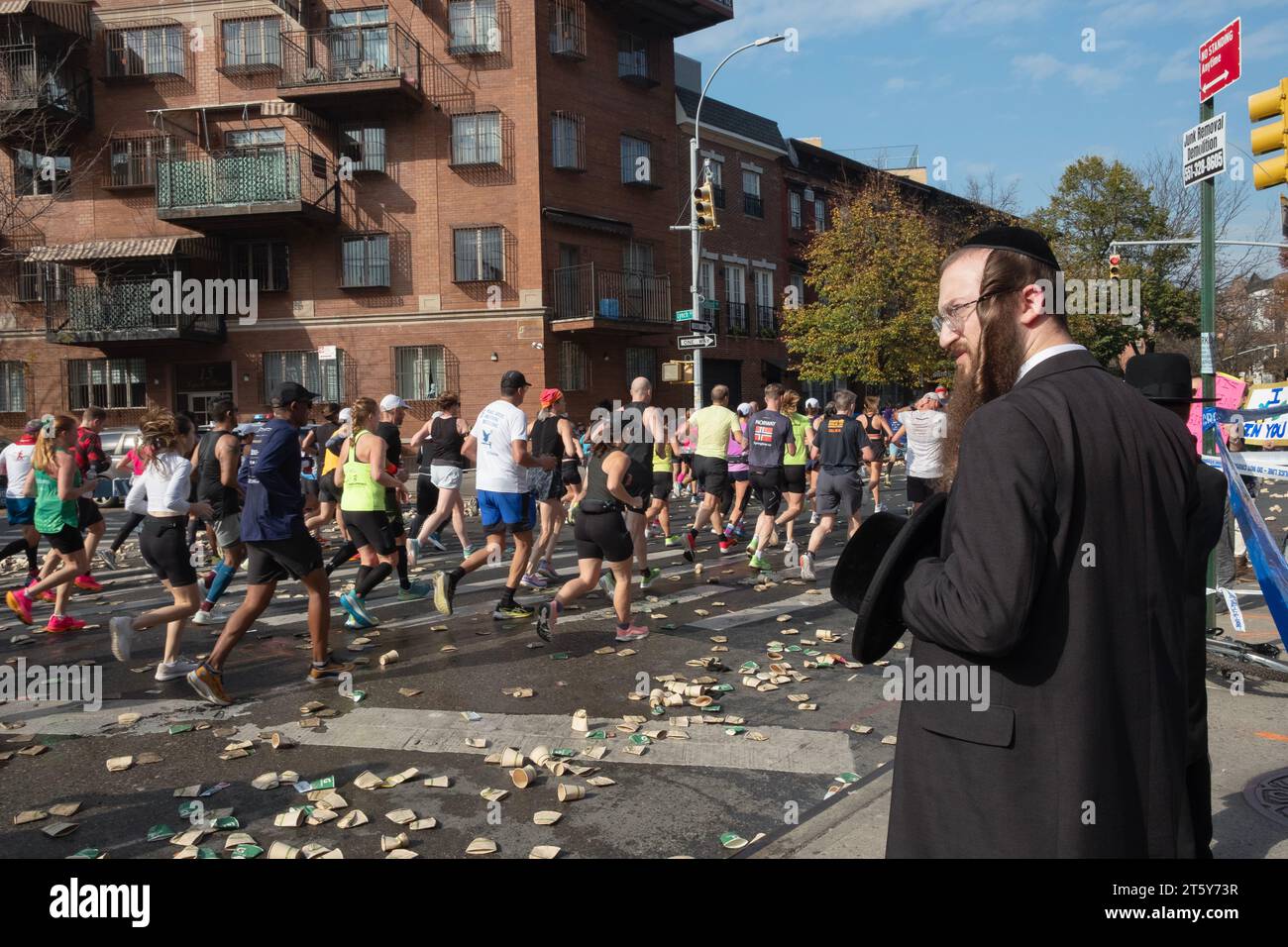 À la marque de 10 miles du marathon de NY un homme juif orthodoxe attend un espace entre les coureurs pour traverser Bedford Ave À Williamsburg, Brooklyn, NY. Banque D'Images