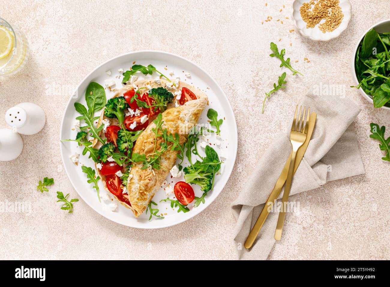 Omelette farcie de tomate, brocoli, fromage feta et feuilles vertes fraîches de roquette et d'épinards. Alimentation saine, petit déjeuner. Vue de dessus Banque D'Images
