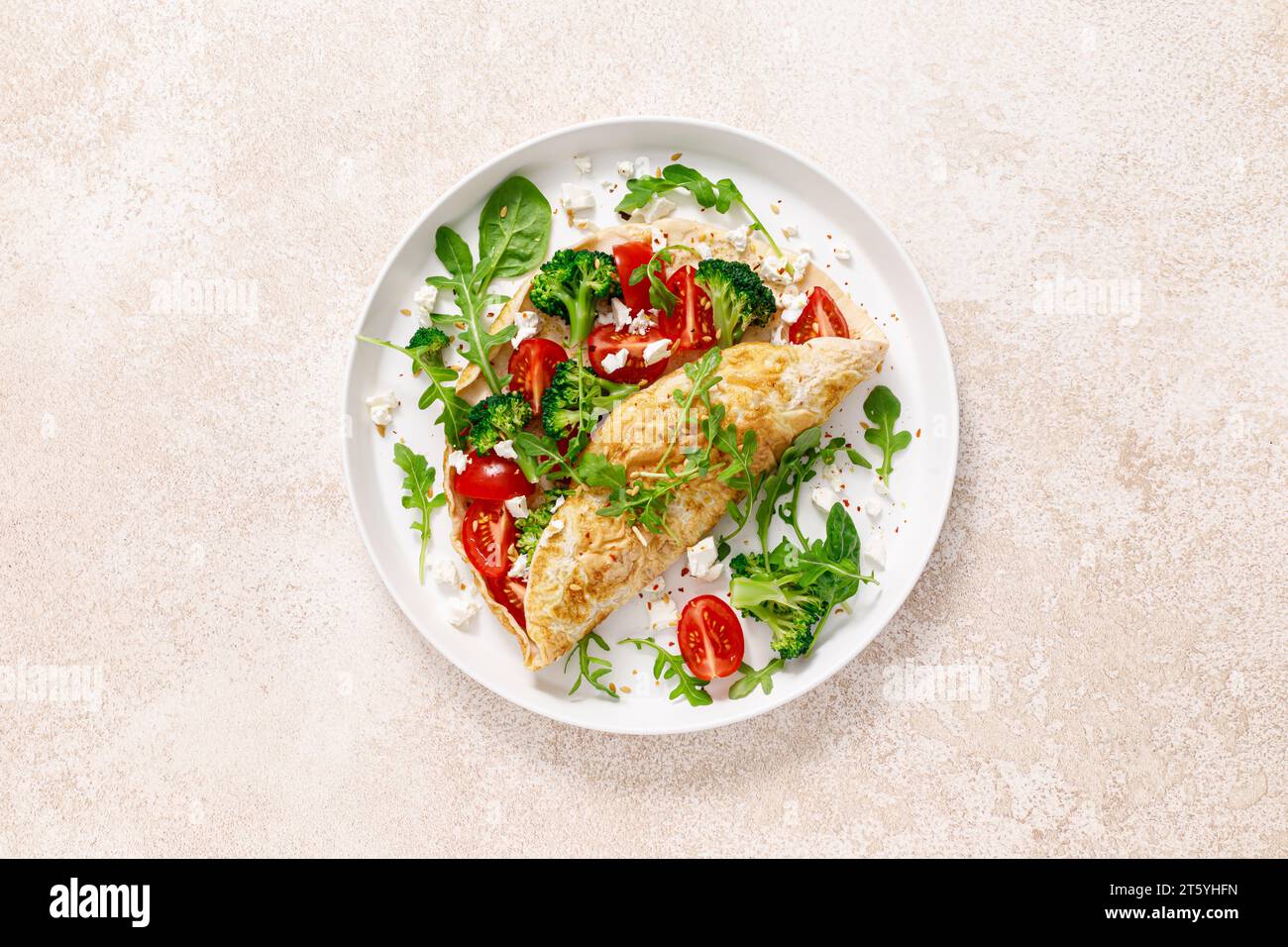 Omelette farcie de tomate, brocoli, fromage feta et feuilles vertes fraîches de roquette et d'épinards. Alimentation saine, petit déjeuner. Vue de dessus Banque D'Images