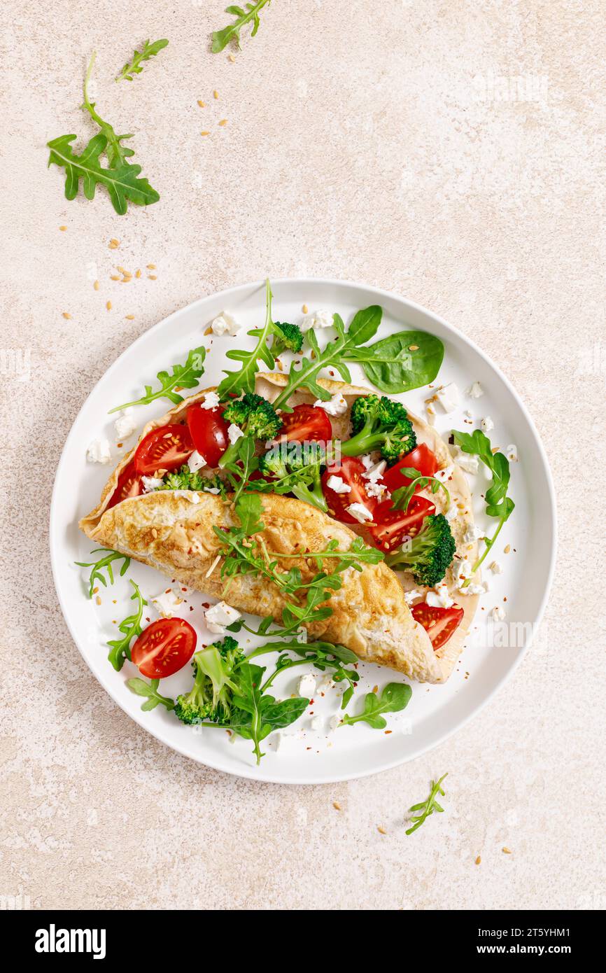 Omelette farcie de tomate, brocoli, fromage feta et feuilles vertes fraîches de roquette et d'épinards. Alimentation saine, petit déjeuner. Vue de dessus Banque D'Images