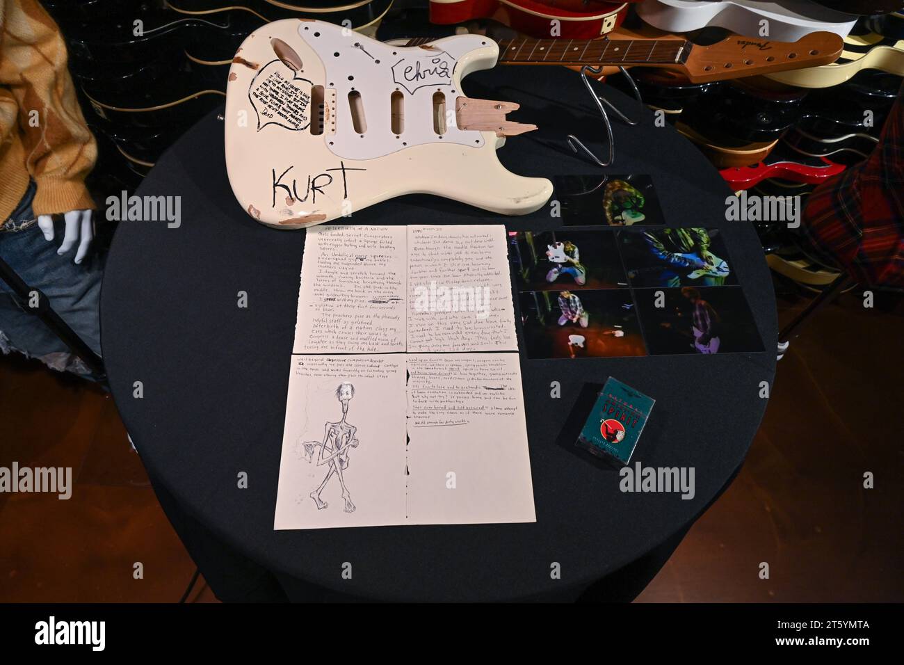 Crème Fender Stratocaster jouée sur scène et cassée de Kurt Cobain, notes manuscrites et croquis et paquet de cigarettes exposés pendant le média Prev Banque D'Images