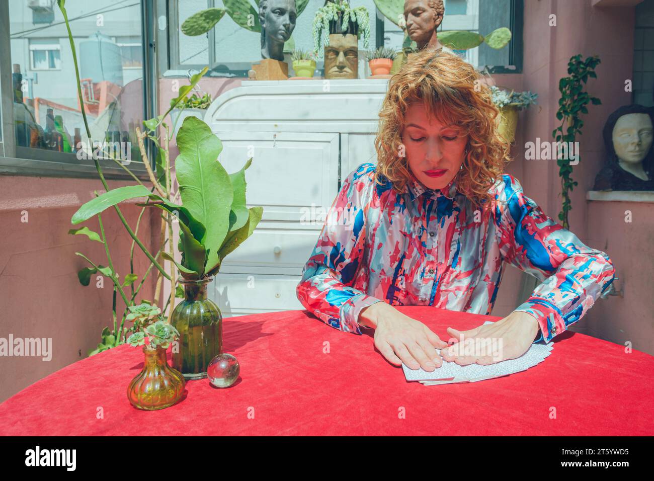 Adulte blonde Argentine lecteur de tarot femme, assise à la maison étalant un jeu de cartes en forme d'éventail sur la table, pour commencer la lecture et la thérapie Banque D'Images