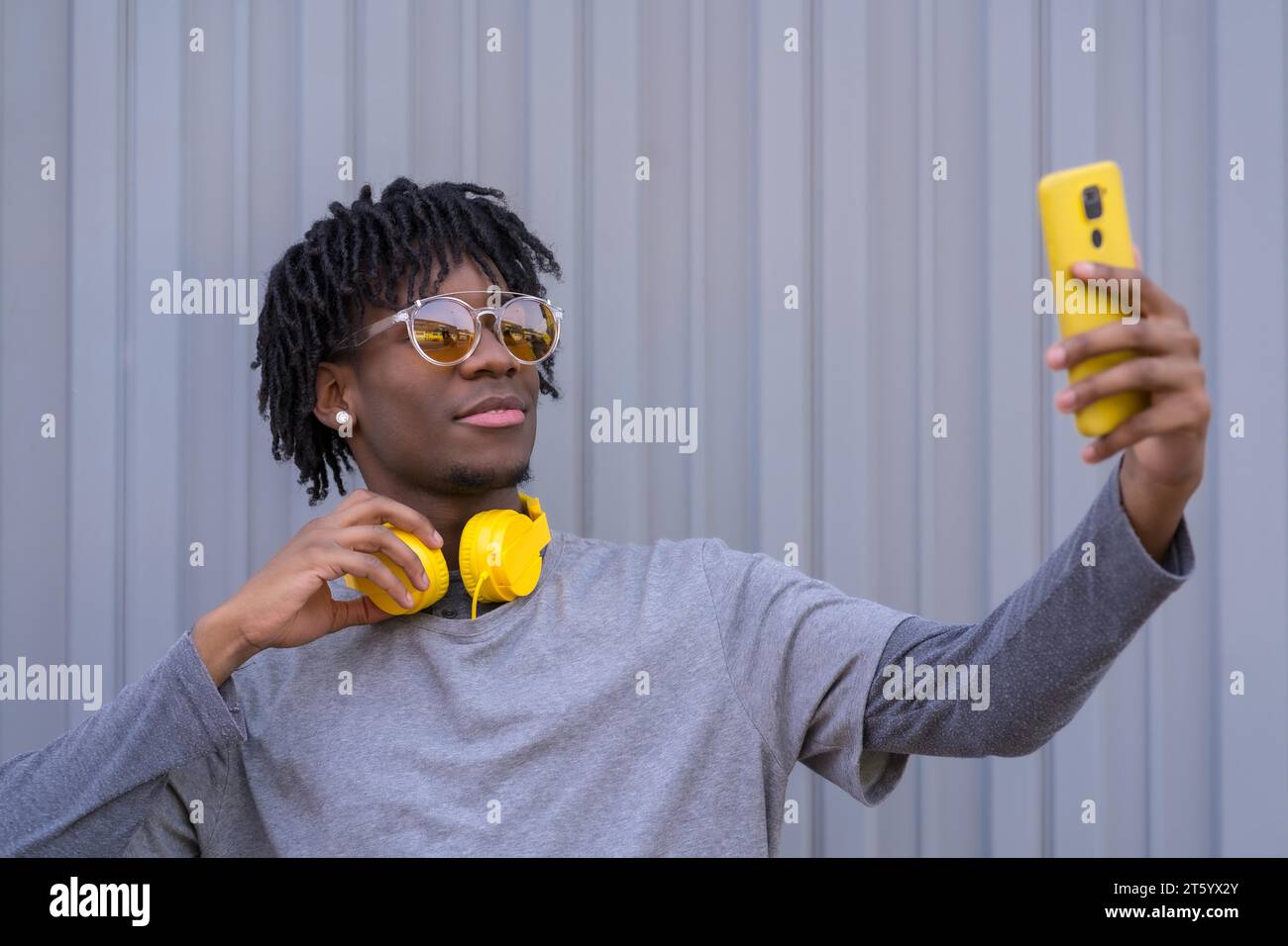 Homme cool africain prenant un selfie à côté d'un mur gris urbain Banque D'Images