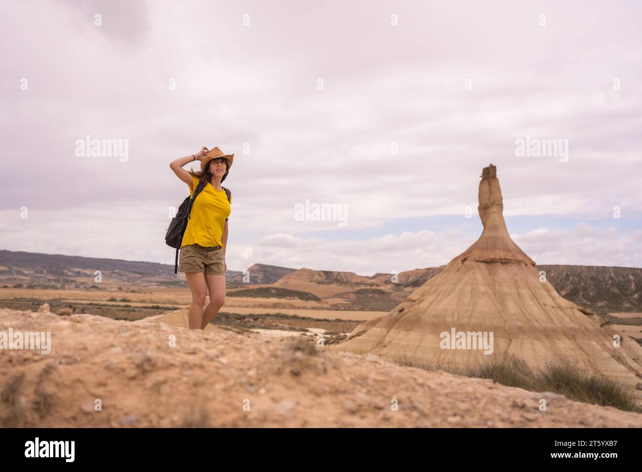 Femme tenant son chapeau pour souffler avec le vent dans un désert Banque D'Images