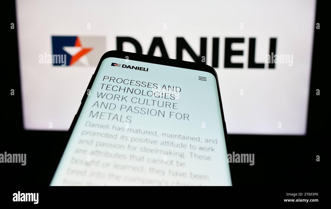 Téléphone portable avec site Internet de la société italienne Danieli C. Officine Meccaniche spa devant le logo de l'entreprise. Effectuez le focus sur le coin supérieur gauche de l'écran du téléphone. Banque D'Images