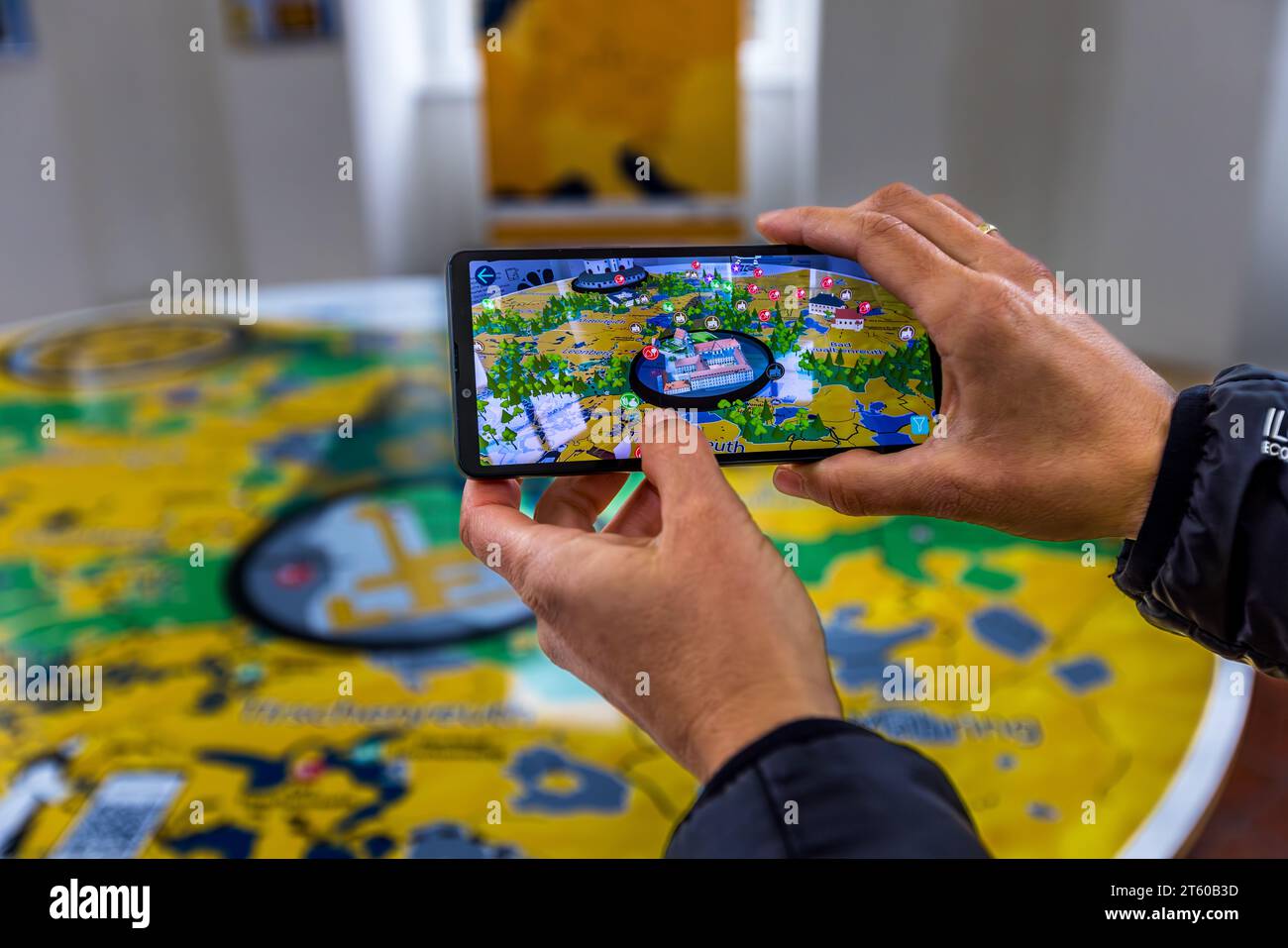Des mains tiennent un smartphone affichant l'application Cisterscapes : en 1133, des moines cisterciens sont arrivés à Waldsassen et ont fondé le monastère, et l'application affiche désormais leurs lieux de travail en 3D. Waldsassen, Bavière, Allemagne. Banque D'Images
