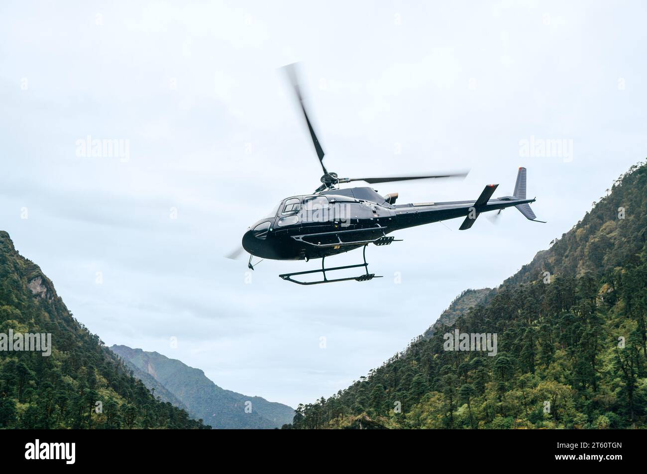 Hélicoptère civil volant dans les montagnes de haute altitude de l'Himalaya près de la colonie de Kothe, Népal. Itinéraire de trekking d'escalade de Mera Peak. Sécurité du transport aérien Banque D'Images