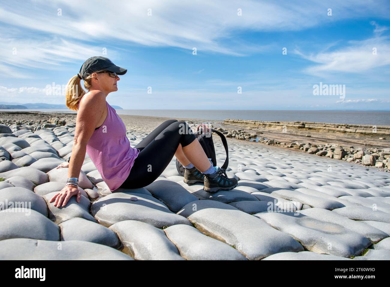 Femme sur la plage de Kilve et la côte rocheuse, à Kilve, Quantocks, Somerset, Royaume-Uni sur une journée ensoleillée. La plage est bien connue pour trouver des fossiles. Banque D'Images