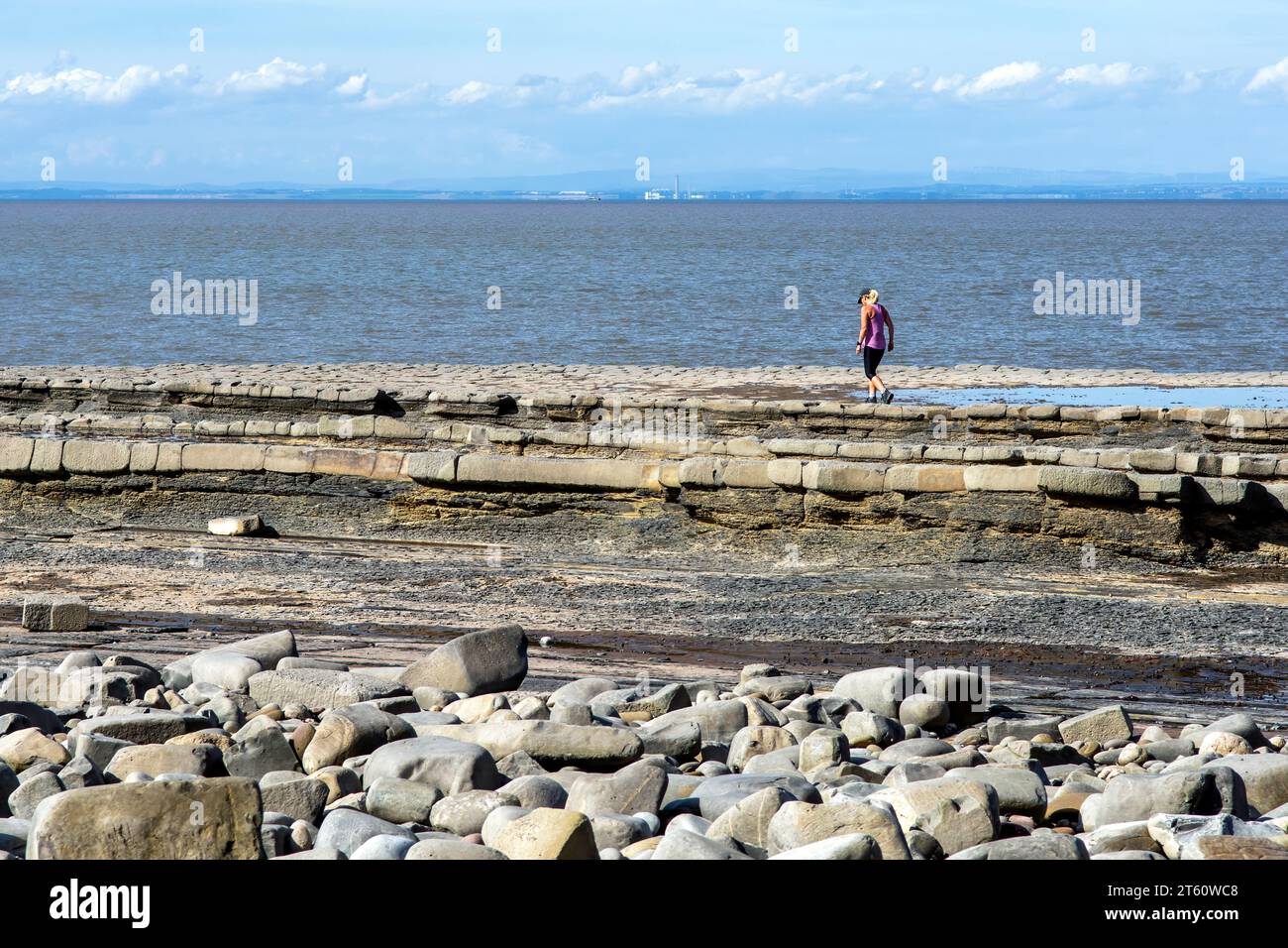 Femme sur la plage de Kilve et la côte rocheuse, à Kilve, Quantocks, Somerset, Royaume-Uni sur une journée ensoleillée. La plage est bien connue pour trouver des fossiles. Banque D'Images