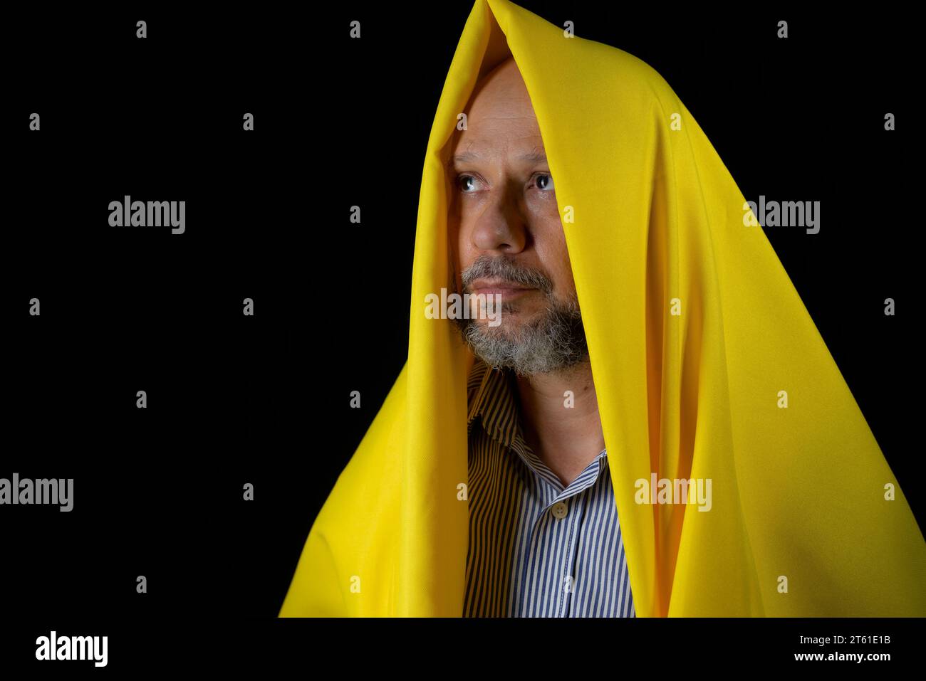 Homme chauve, barbu avec un tissu jaune sur la tête sur fond noir. Banque D'Images