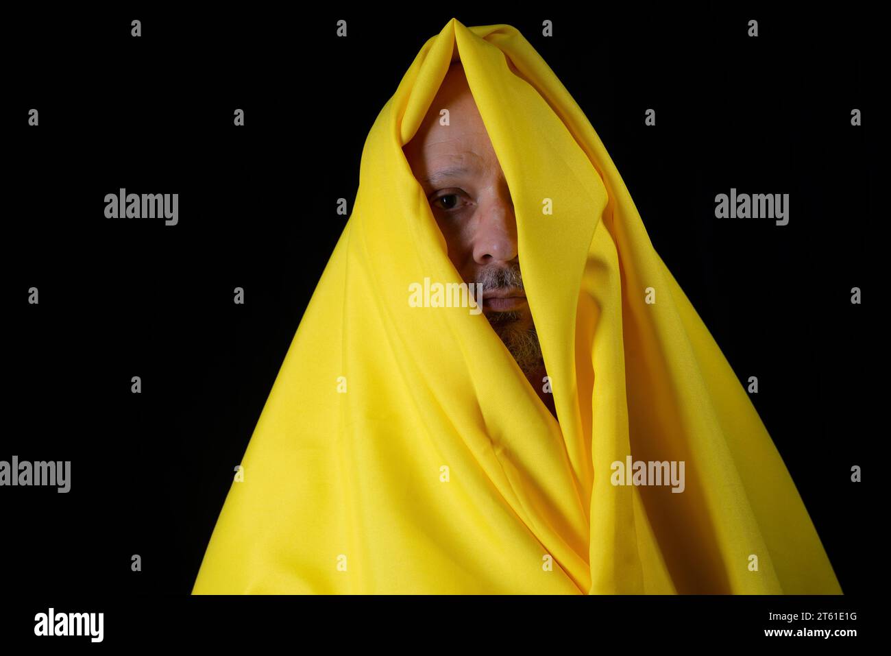 Homme chauve, barbu avec un tissu jaune sur la tête sur fond noir. Banque D'Images