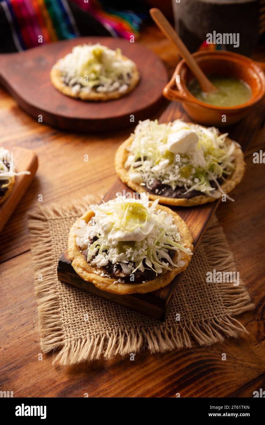 Sopes. Cuisine mexicaine traditionnelle maison préparée avec aplatie et pincée sur la bordure pâte de maïs frite recouverte de haricots frits, verts ou rouges Banque D'Images