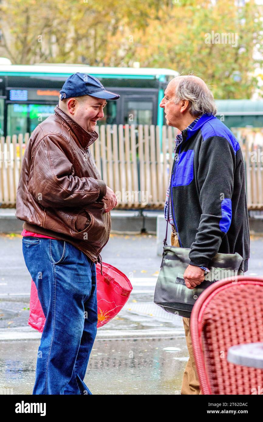 Deux amis masculins discutant au coin de la rue - Paris 20, France. Banque D'Images