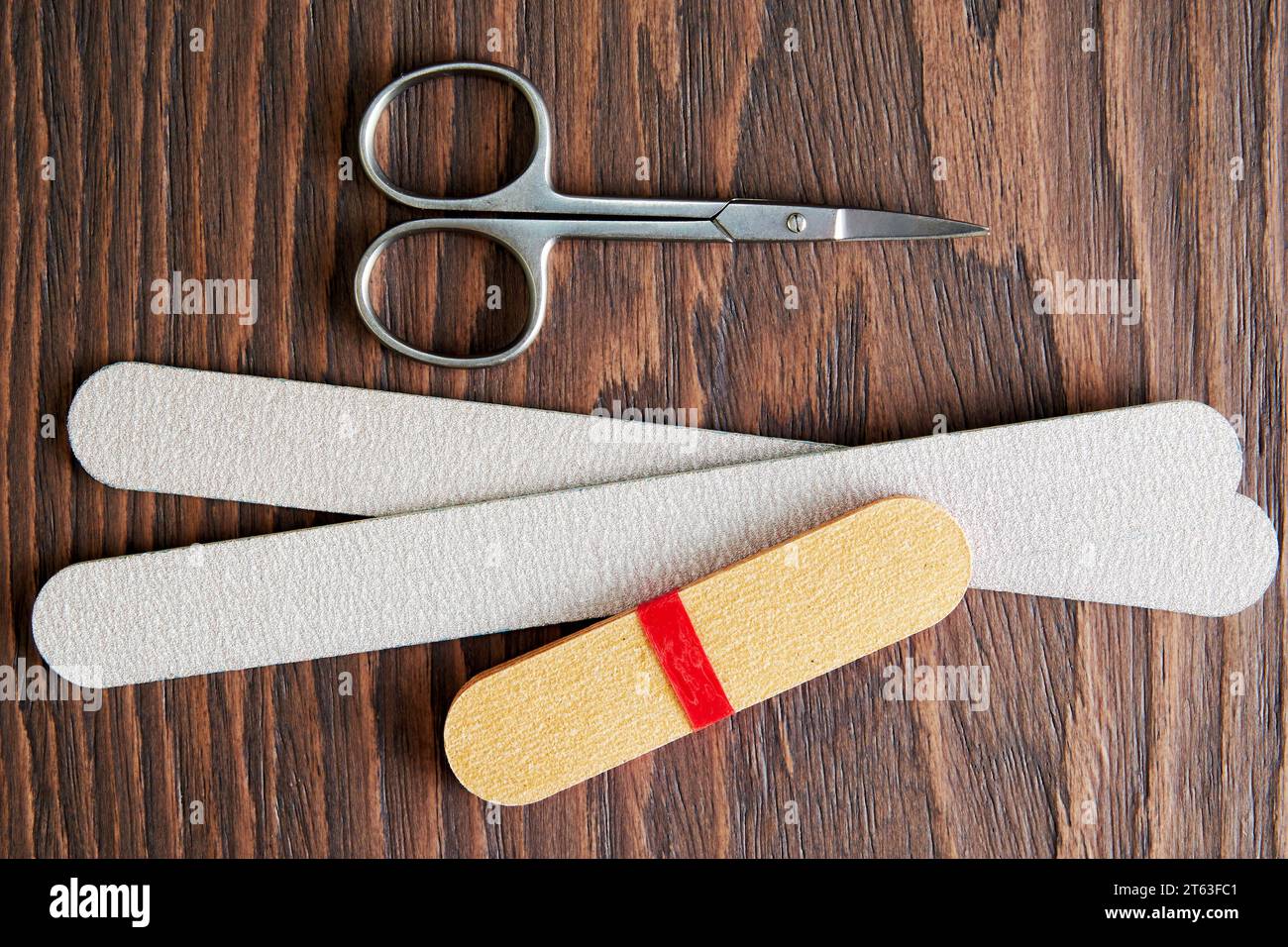 Poser à plat avec des outils de manucure, des ciseaux et une lime à ongles sur la table en bois brut. Équipement cosmétique. Soin du corps et thème de la mode Banque D'Images