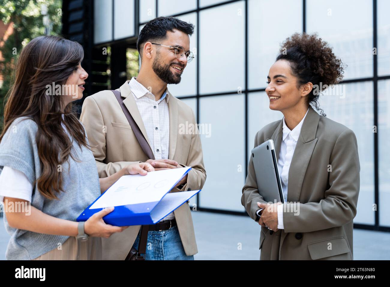 Groupe diversifié de jeunes gens d'affaires à l'extérieur de l'immeuble de bureaux, discutant et parlant homme et femme résolvant le nouveau plan de construction, équipe d'affaires e Banque D'Images